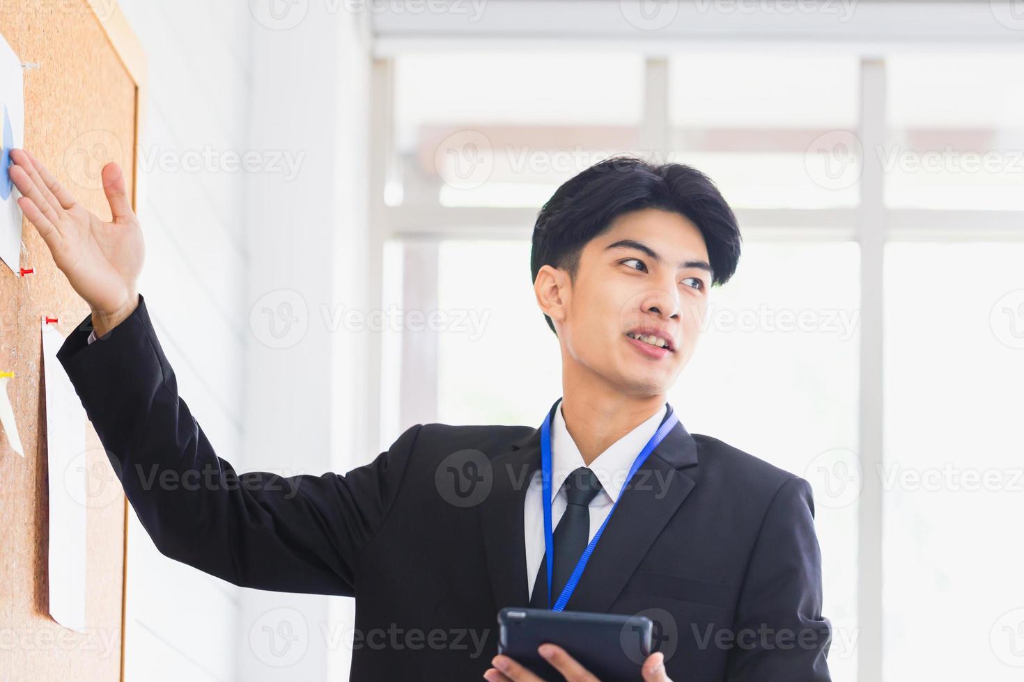 uomo d'affari che fa una presentazione davanti al bordo, il dipendente maschio spiega i dati aziendali a bordo nella sala riunioni dell'ufficio foto