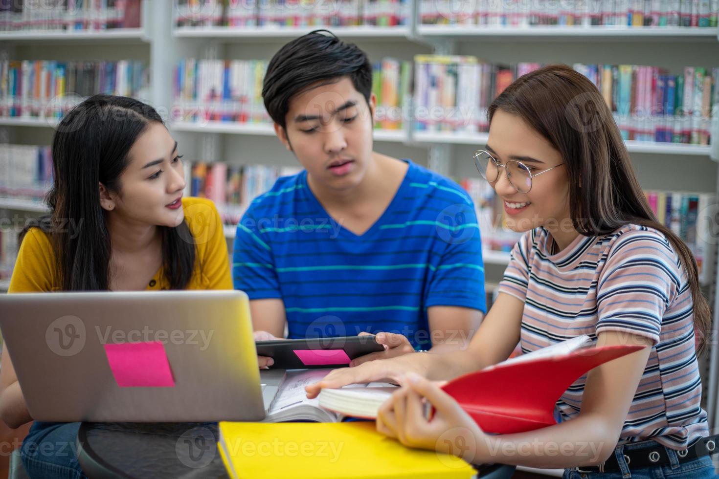 gli studenti asiatici di gruppo sorridono e leggono un libro e usano il taccuino per aiutare a condividere idee nel lavoro e nel progetto. e anche rivedere il libro prima dell'esame foto