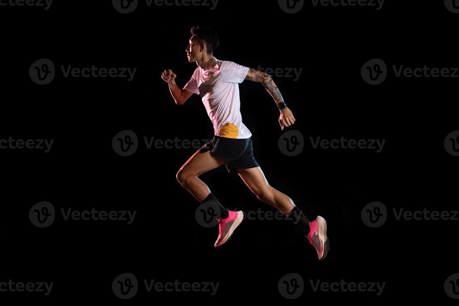 uomo asiatico giovane corridore velocista in esecuzione in studio su sfondo nero foto