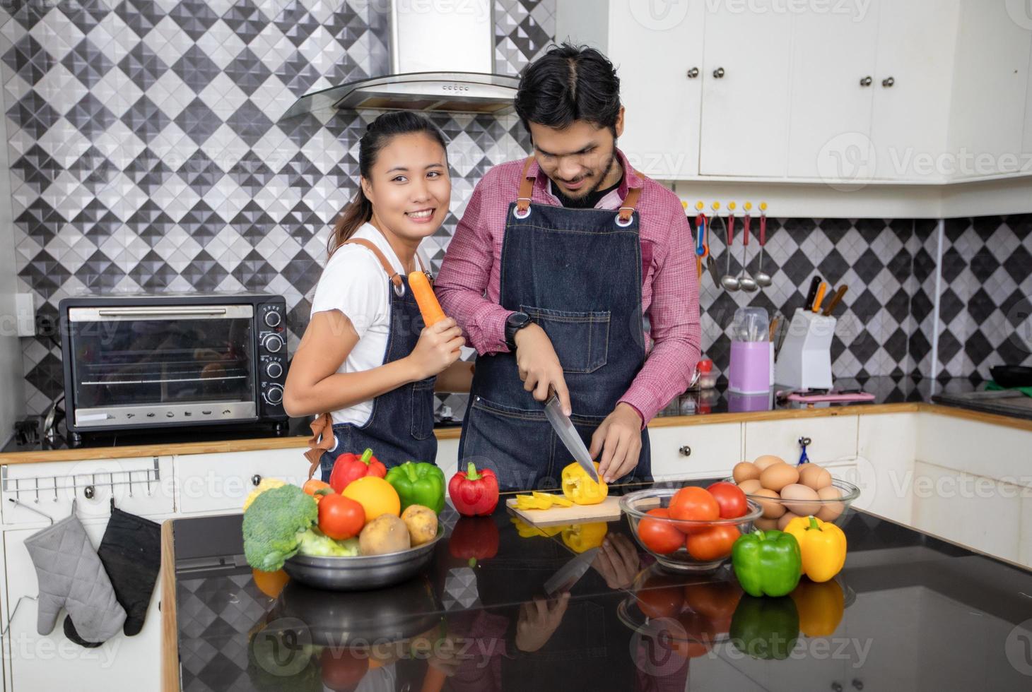 giovane coppia felice e sorridente che cucina cibo nella cucina di casa foto