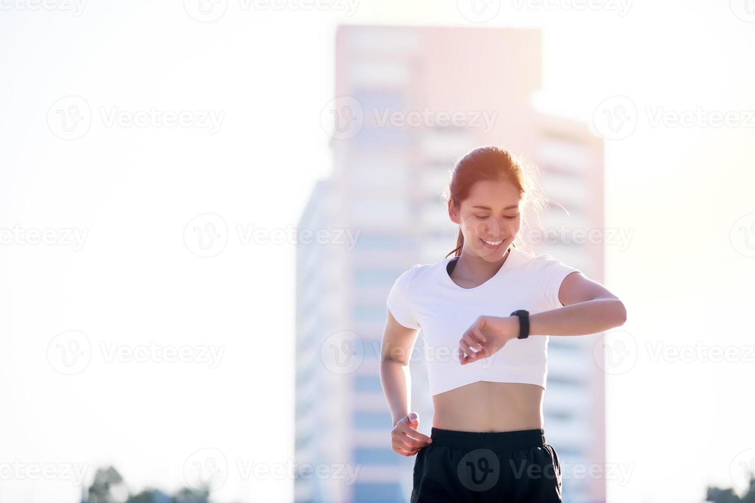 le donne asiatiche stanno guardando l'orologio sportivo o l'orologio intelligente per fare jogging in città foto