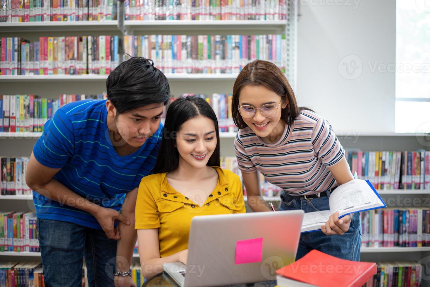 gli studenti asiatici di gruppo sorridono e leggono un libro e usano il taccuino per aiutare a condividere idee nel lavoro e nel progetto. e anche rivedere il libro prima dell'esame foto