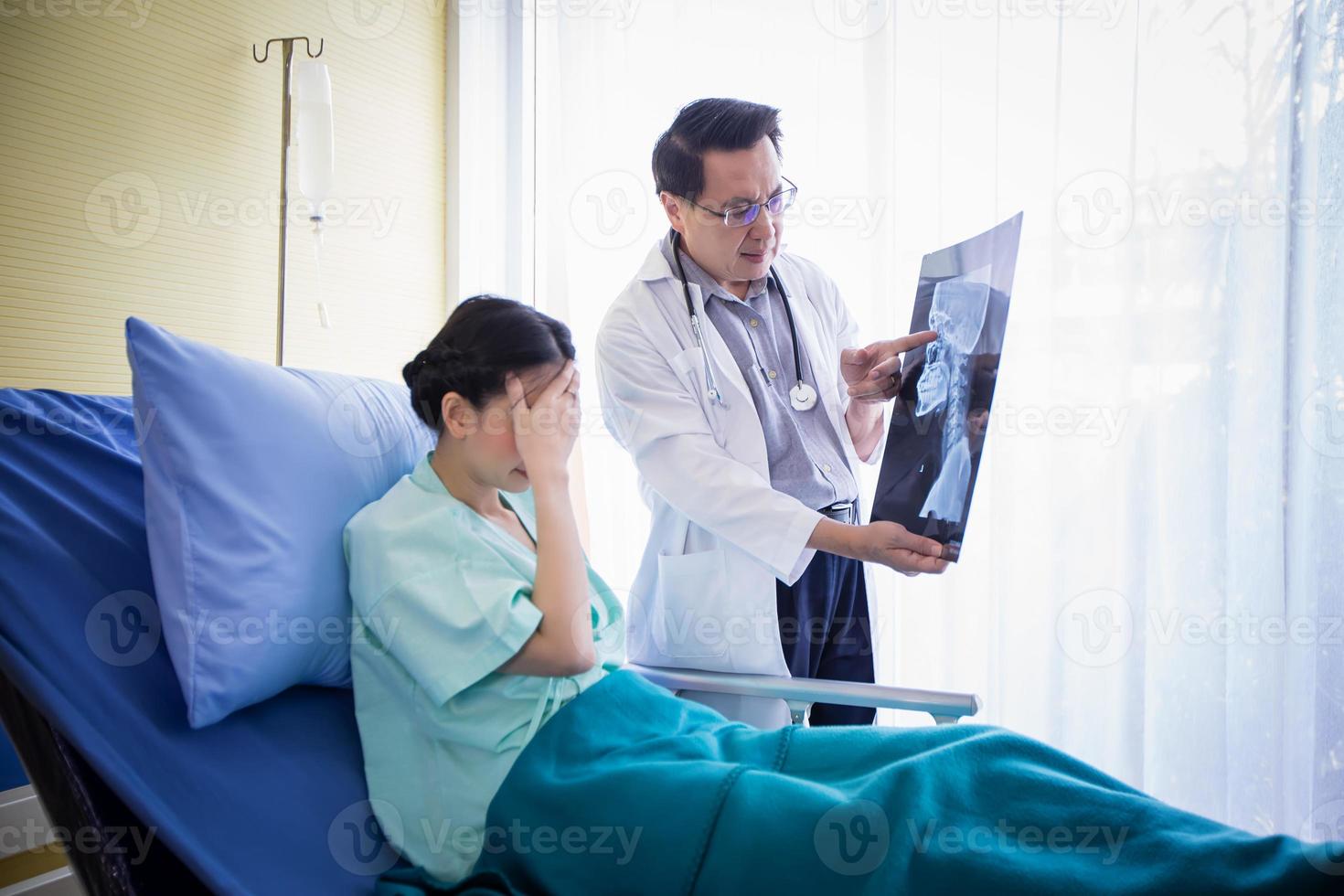 il dottore sta spiegando i risultati della radiografia cerebrale a una paziente sdraiata a letto in un ospedale foto