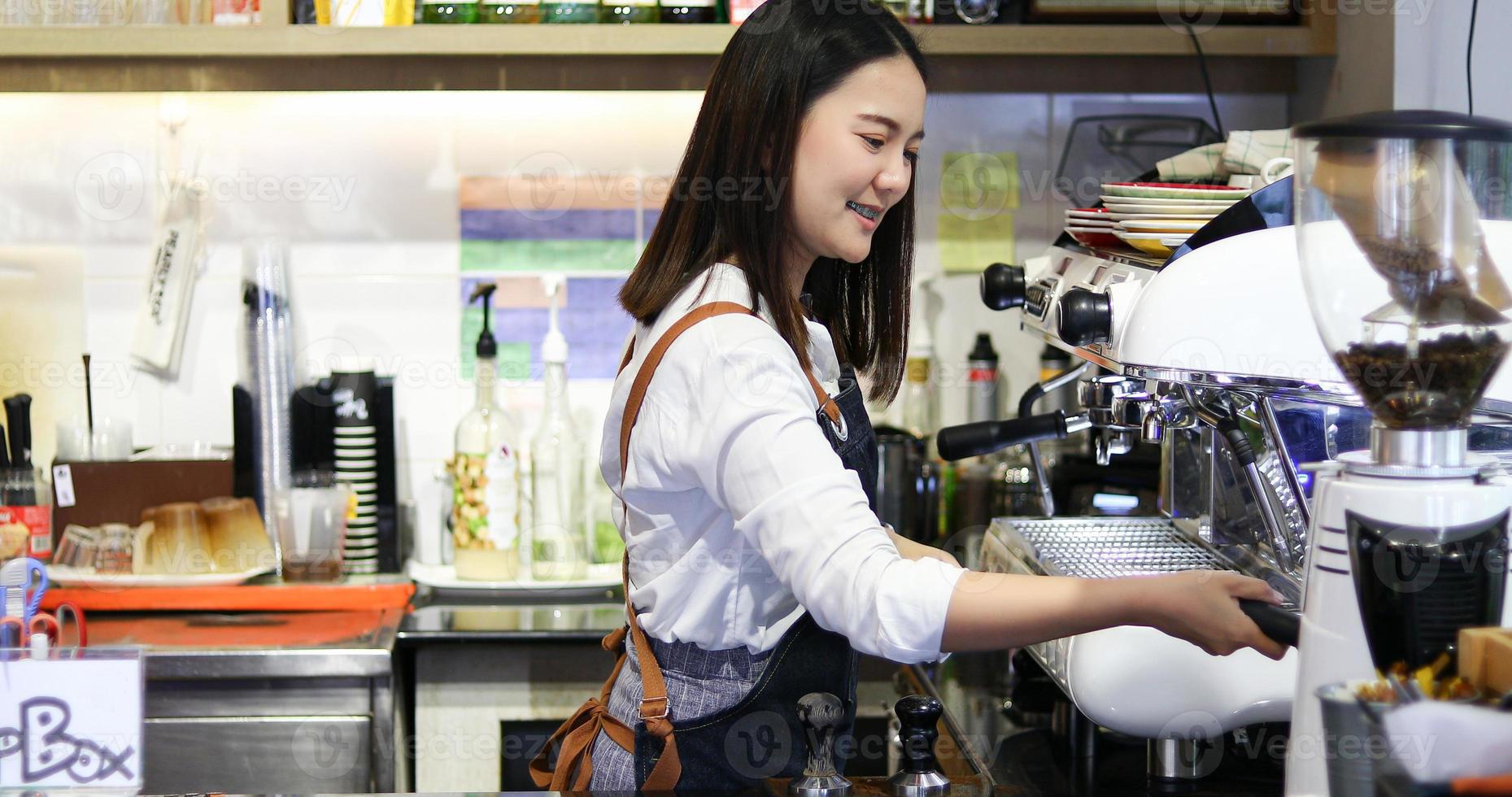 barista delle donne asiatiche che sorride e usa la macchina da caffè nel bancone della caffetteria - donna che lavora proprietario di una piccola impresa cibo e bevande concetto di caffè foto