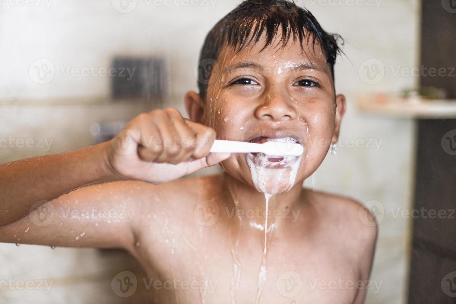 ragazzo asiatico lavarsi i denti con schiuma che esce dalla sua bocca foto