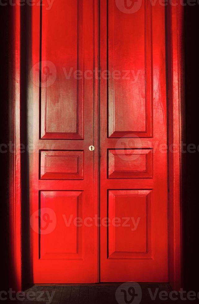 sedia vuota alla luce dietro enormi porte vintage rosse per interni. concetto di interni vecchio stile foto