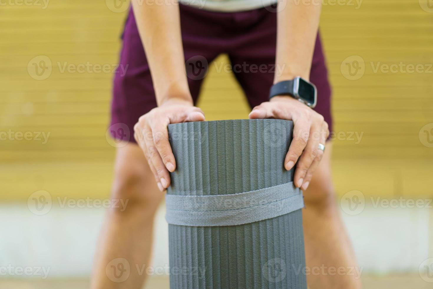 sportivo asiatico attivo che prepara - srotolando un esercizio o un tappetino da yoga, un corpo sano e in forma di un uomo sportivo asiatico che prepara un tappetino da yoga da allenamento per il peso corporeo e l'esercizio cardio. foto