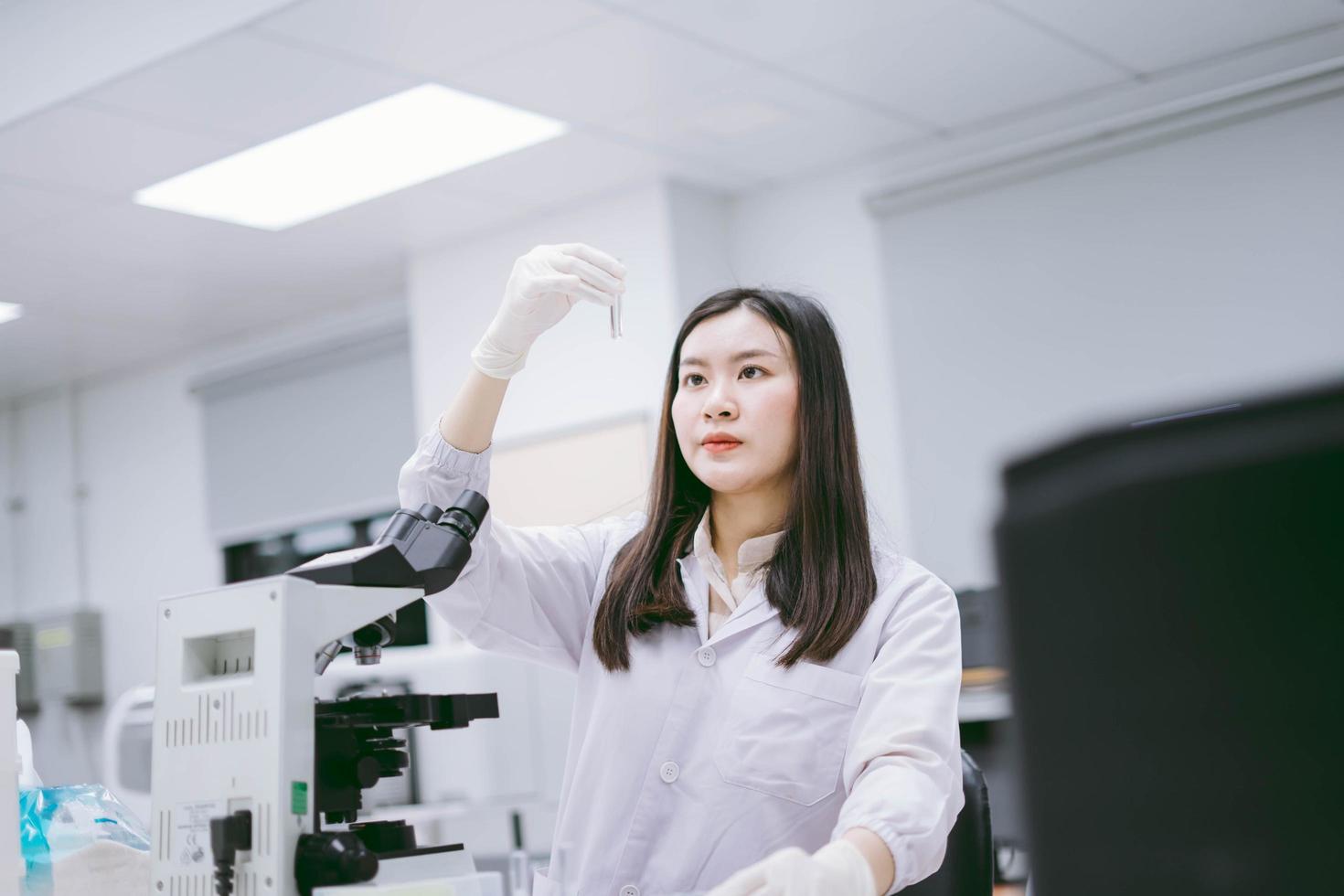 giovane scienziata medica che esamina la provetta in laboratorio medico foto