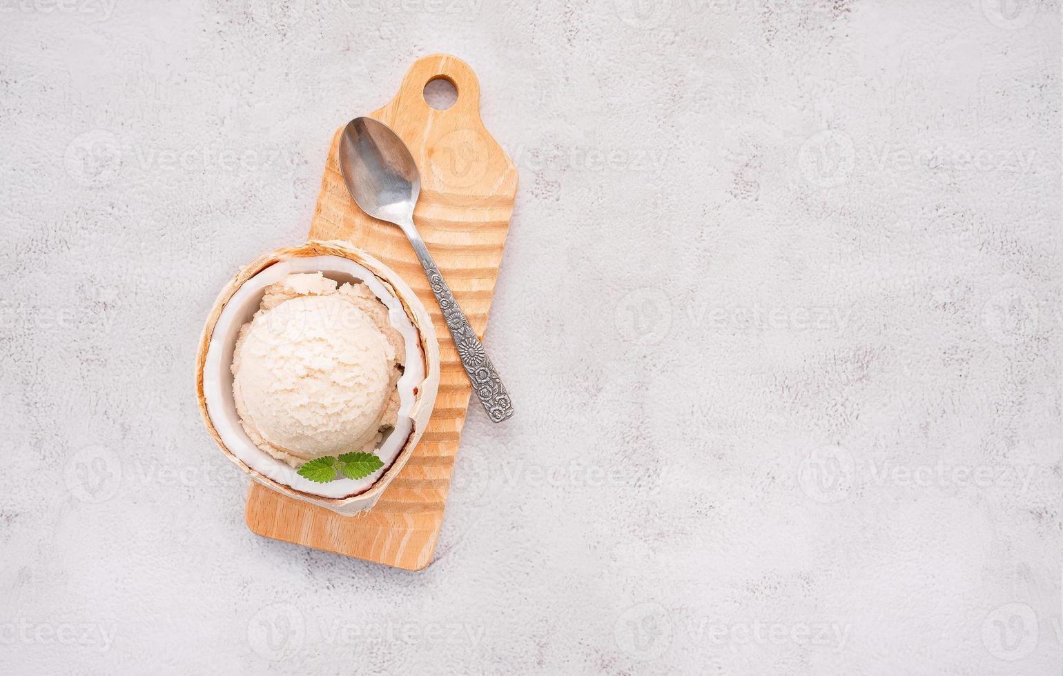 gusti di gelato al cocco a metà della configurazione di cocco su sfondo di pietra bianca. concetto di menu estivo e dolce. foto