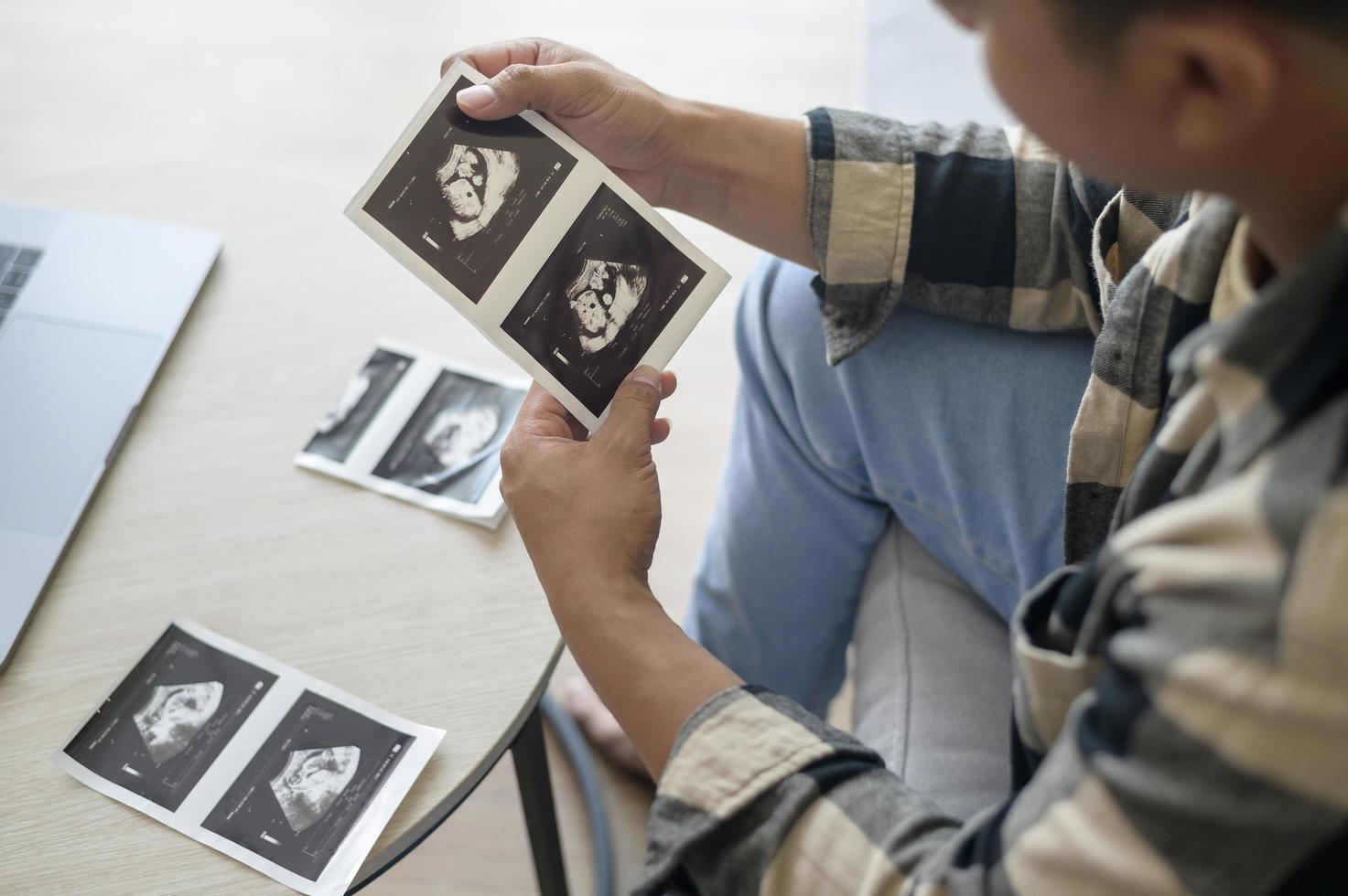 giovane padre che tiene una foto ad ultrasuoni del neonato, della maternità e del concetto di famiglia