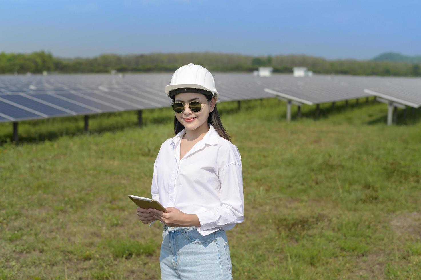 ingegnere femminile che indossa il casco nella fattoria delle celle fotovoltaiche o nel campo dei pannelli solari, energia ecologica e pulita. foto