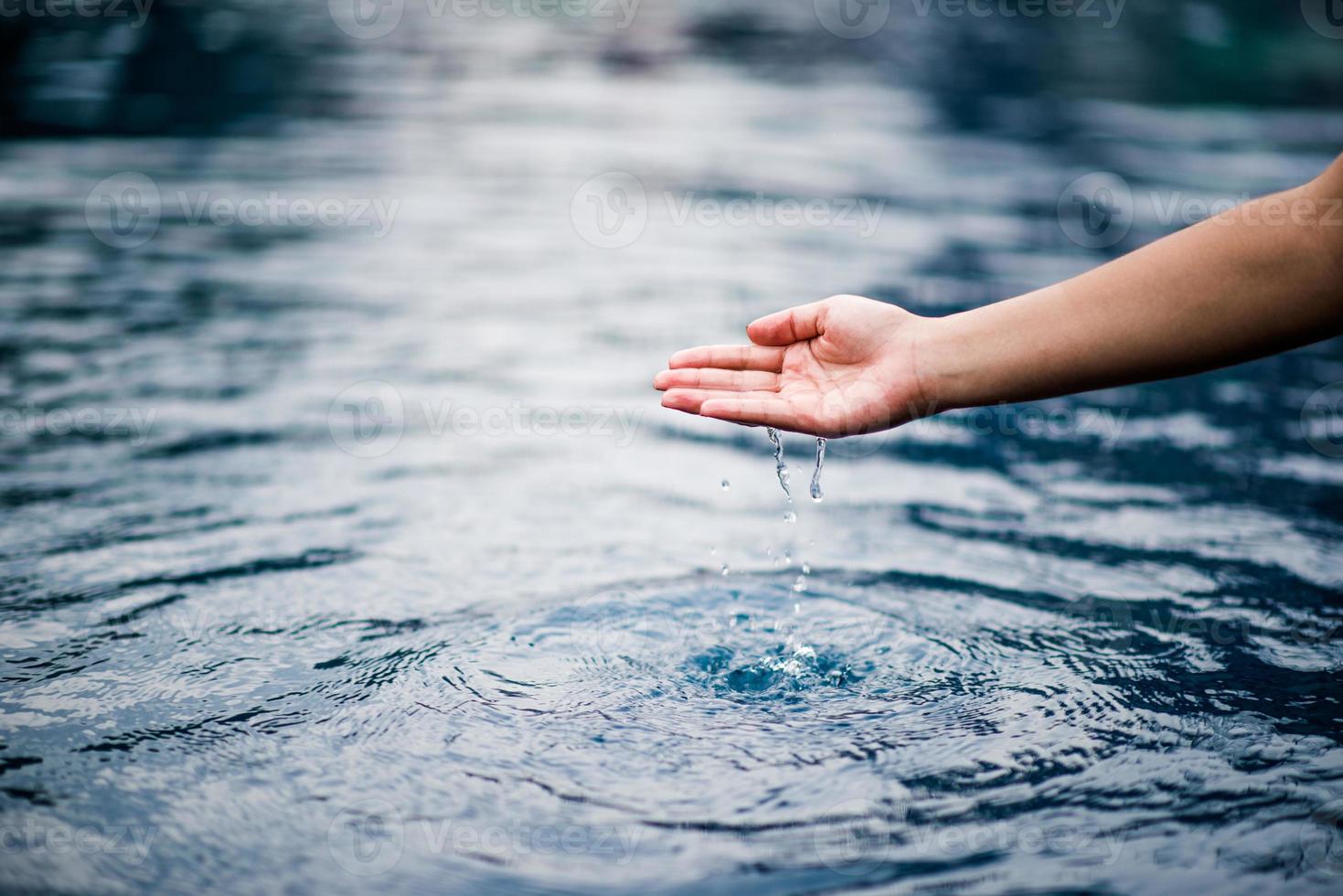 la mano che tocca l'acqua azzurra. la piscina è pulita e luminosa. con una goccia d'acqua sull'acqua. foto