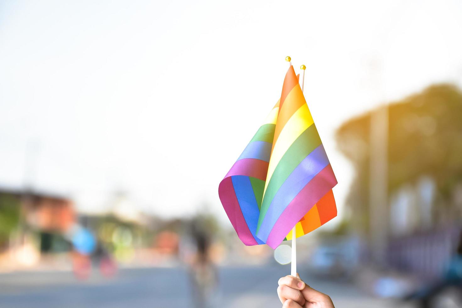 orgoglio arcobaleno lgbt bandiera gay che tiene in mano e viene sventolata nella brezza contro il cielo blu. foto