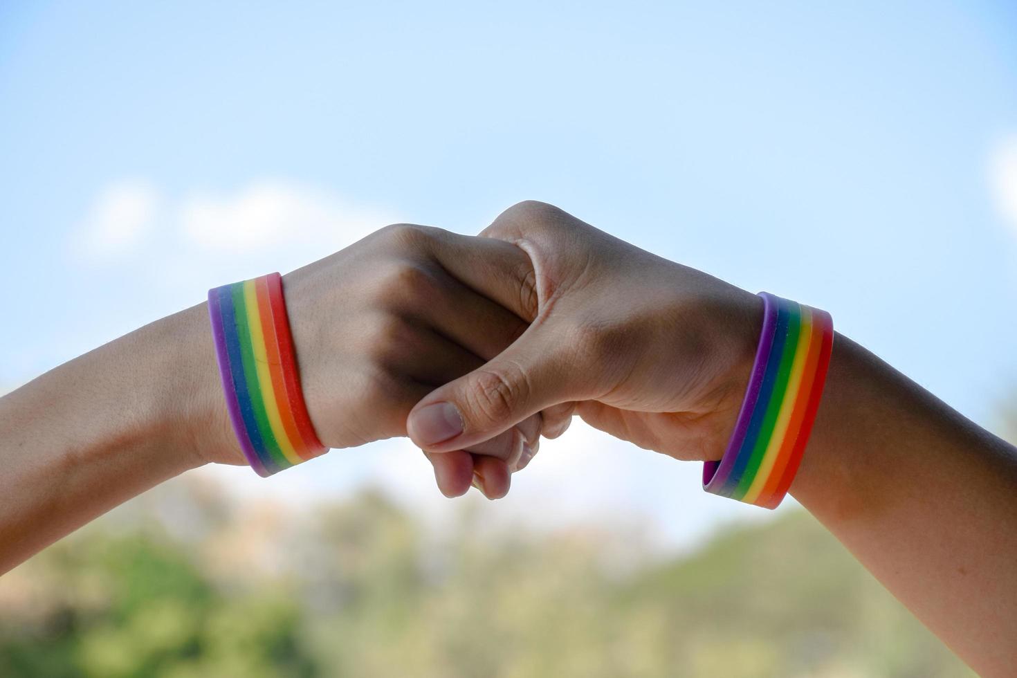 braccialetti di gomma arcobaleno nei polsi di una coppia di ragazzi asiatici con sfondo sfocato, concetto per la celebrazione della comunità lgbt nel mese dell'orgoglio o nel giugno in tutto il mondo. foto