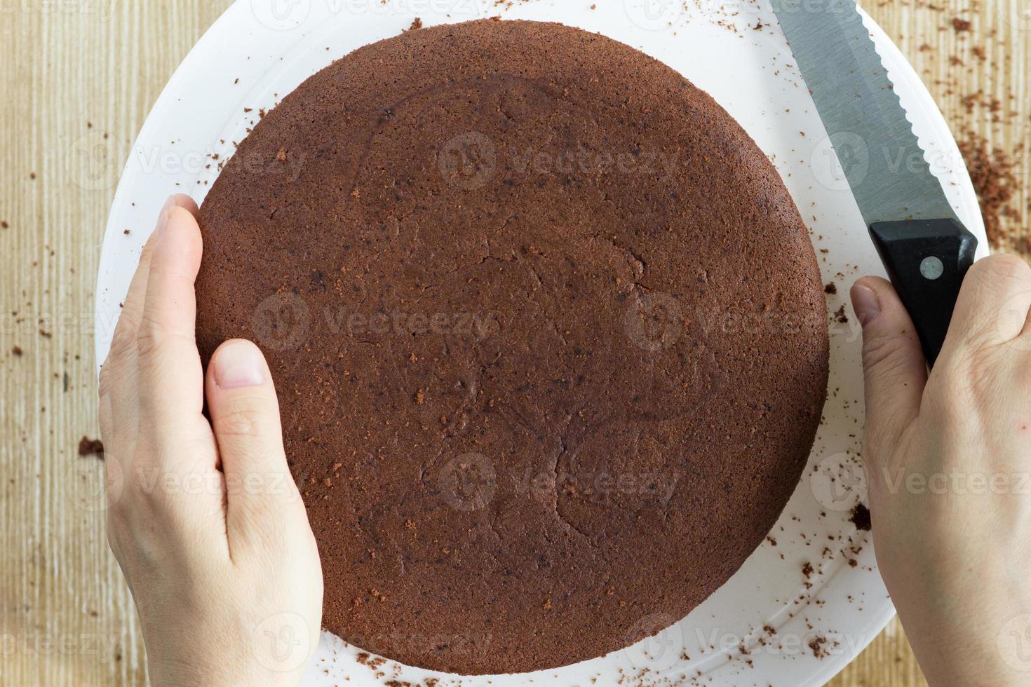 pan di spagna al cioccolato al forno e mani con coltello da tagliare foto