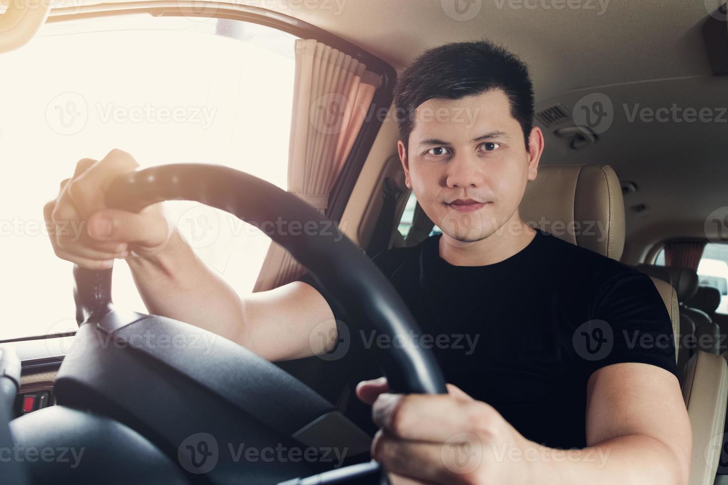 godendo la sua guida. bel giovane in maglietta nera che sorride mentre guida un'auto di stato, foto vintage.