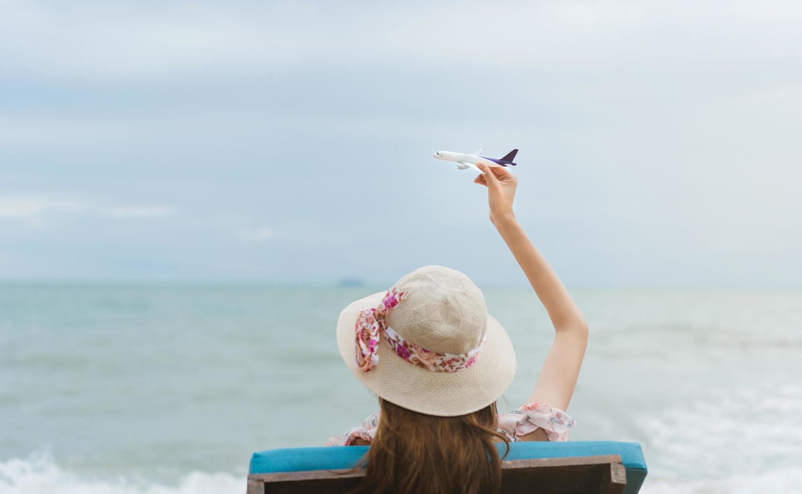 asiatico viaggiatore donna tenere modello aereo in cielo foto