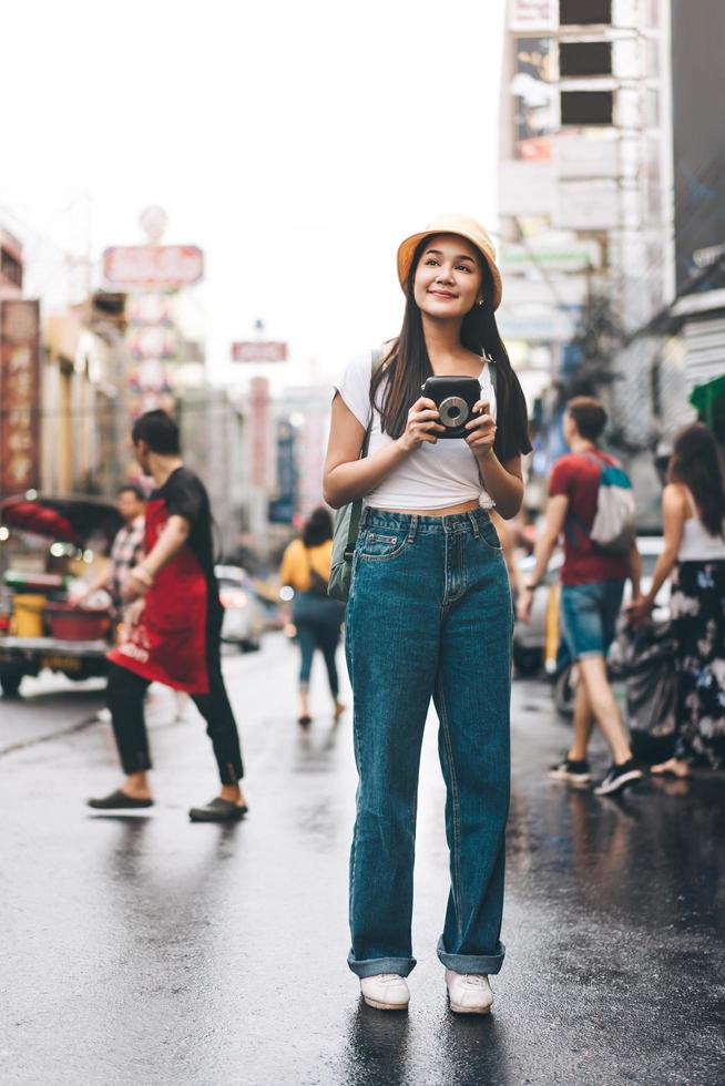 giovane donna asiatica del viaggiatore con la macchina fotografica istantanea a bangkok, tailandia foto