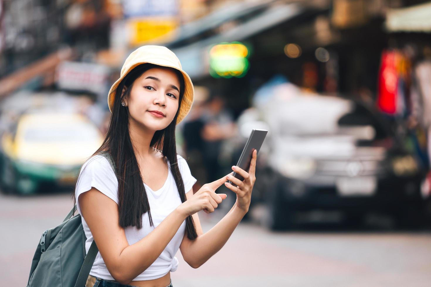 la donna solista che fa un giro turistico con la tecnologia moderna usa lo smartphone per il taxi. foto