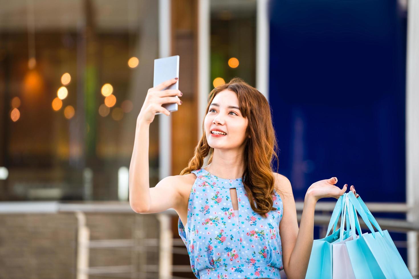 la giovane donna asiatica del cliente usa lo smartphone con le borse della spesa foto