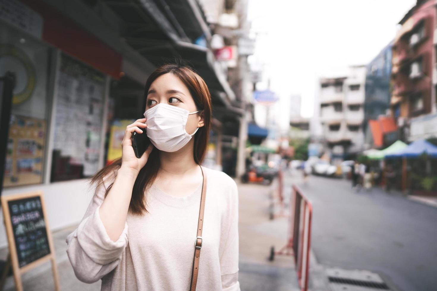 affari casuali giovane donna asiatica single indossa una maschera per il nuovo stile di vita normale in città foto