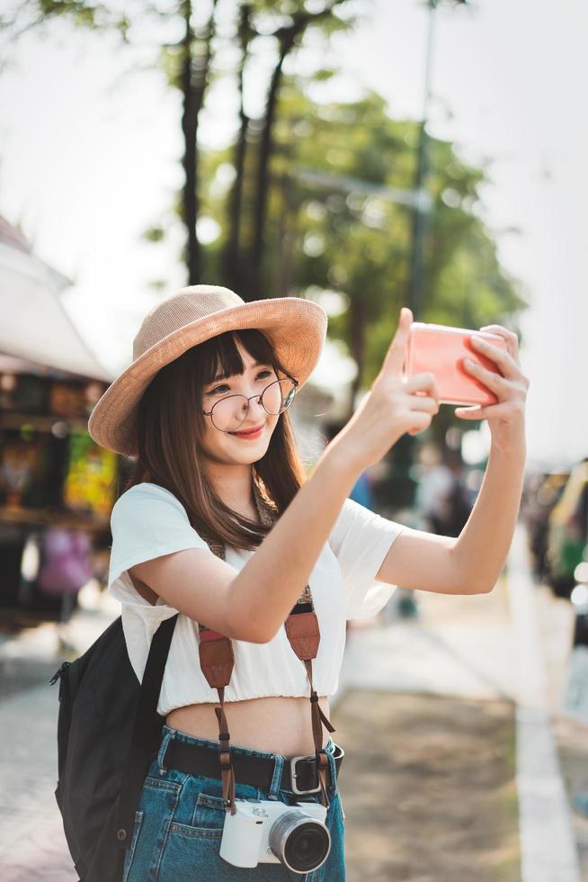 giovane ragazza asiatica di influenza che viaggia a Bangkok con lo smartphone per il caricamento sul social network. foto