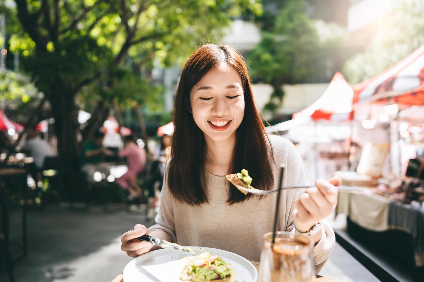 la giovane donna asiatica adulta mangia il cibo per il pranzo al ristorante all'aperto il giorno del fine settimana foto