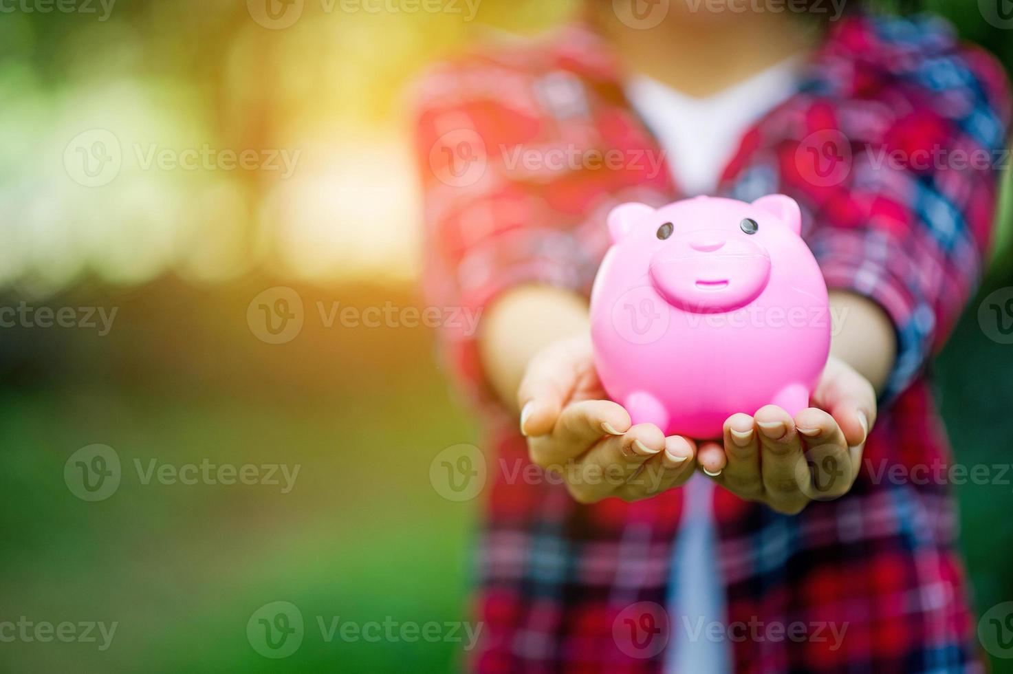 mano femminile che tiene salvadanaio rosa, salvadanaio e felice con i risparmi. e copia spazio foto