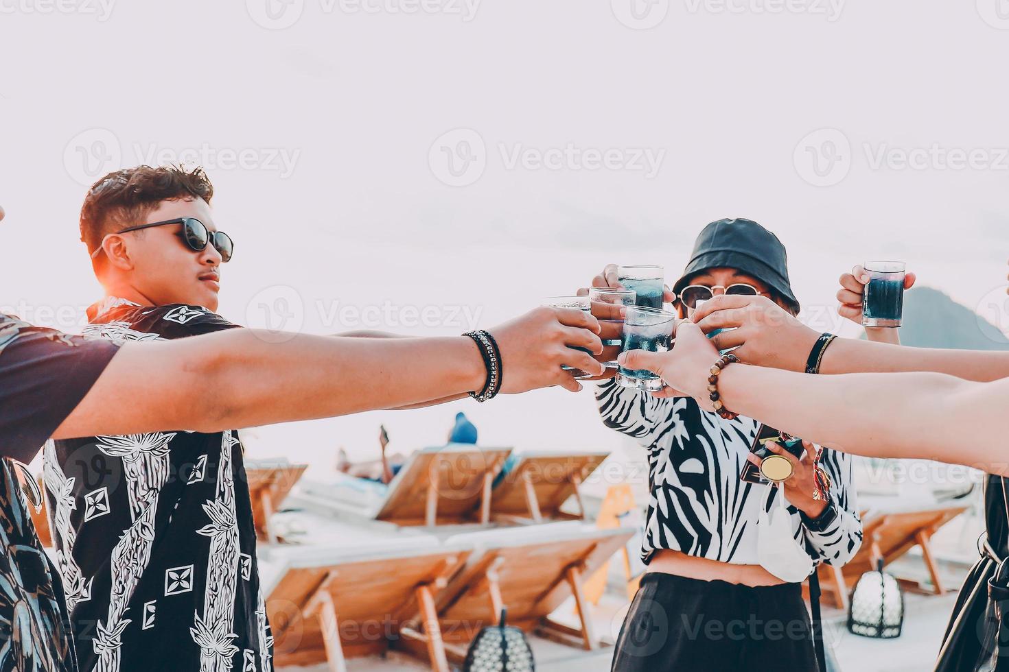 gruppo di amici asiatici che fanno il tifo con cocktail tropicali blu durante le vacanze estive foto