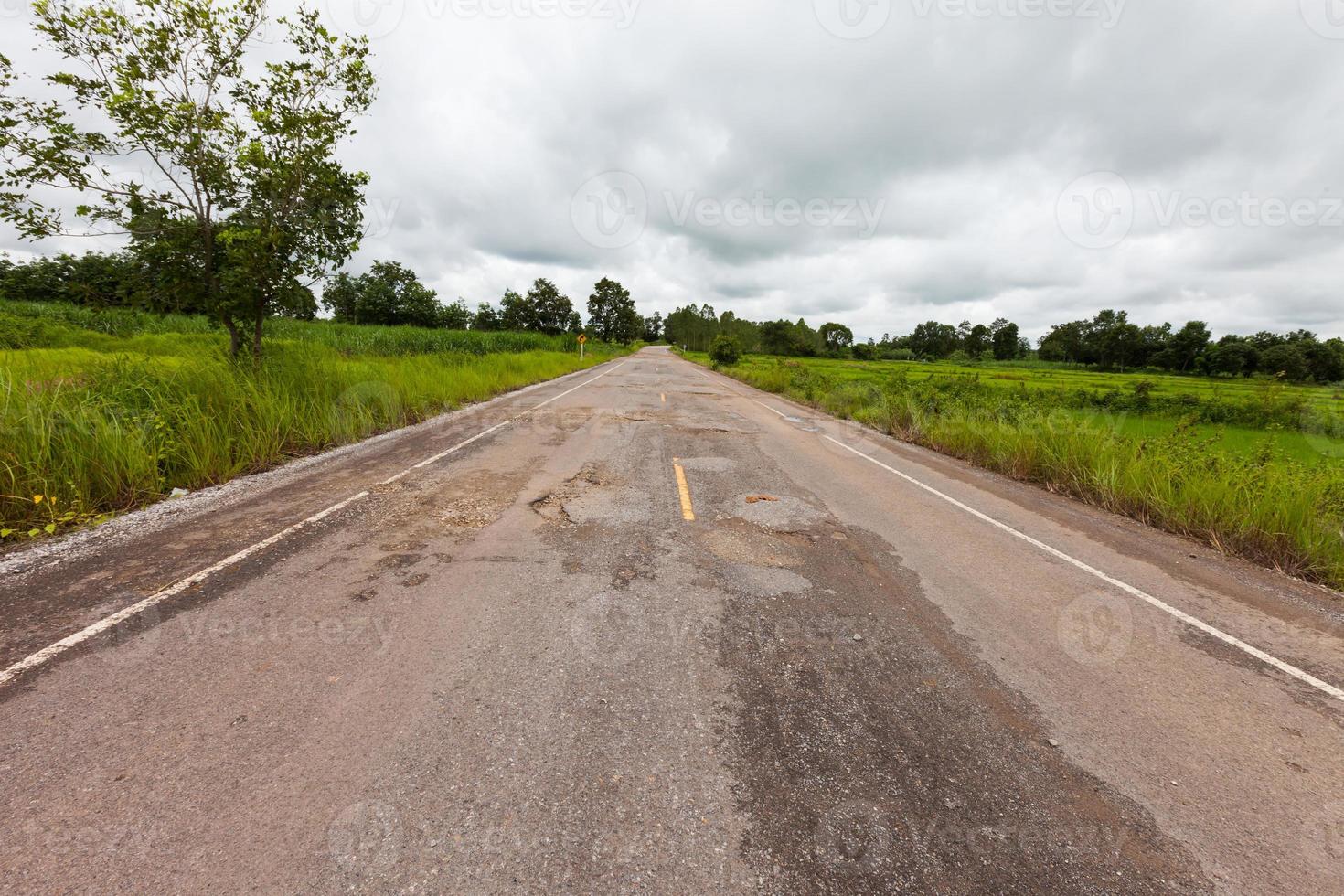 strada asfaltata danneggiata con buche foto