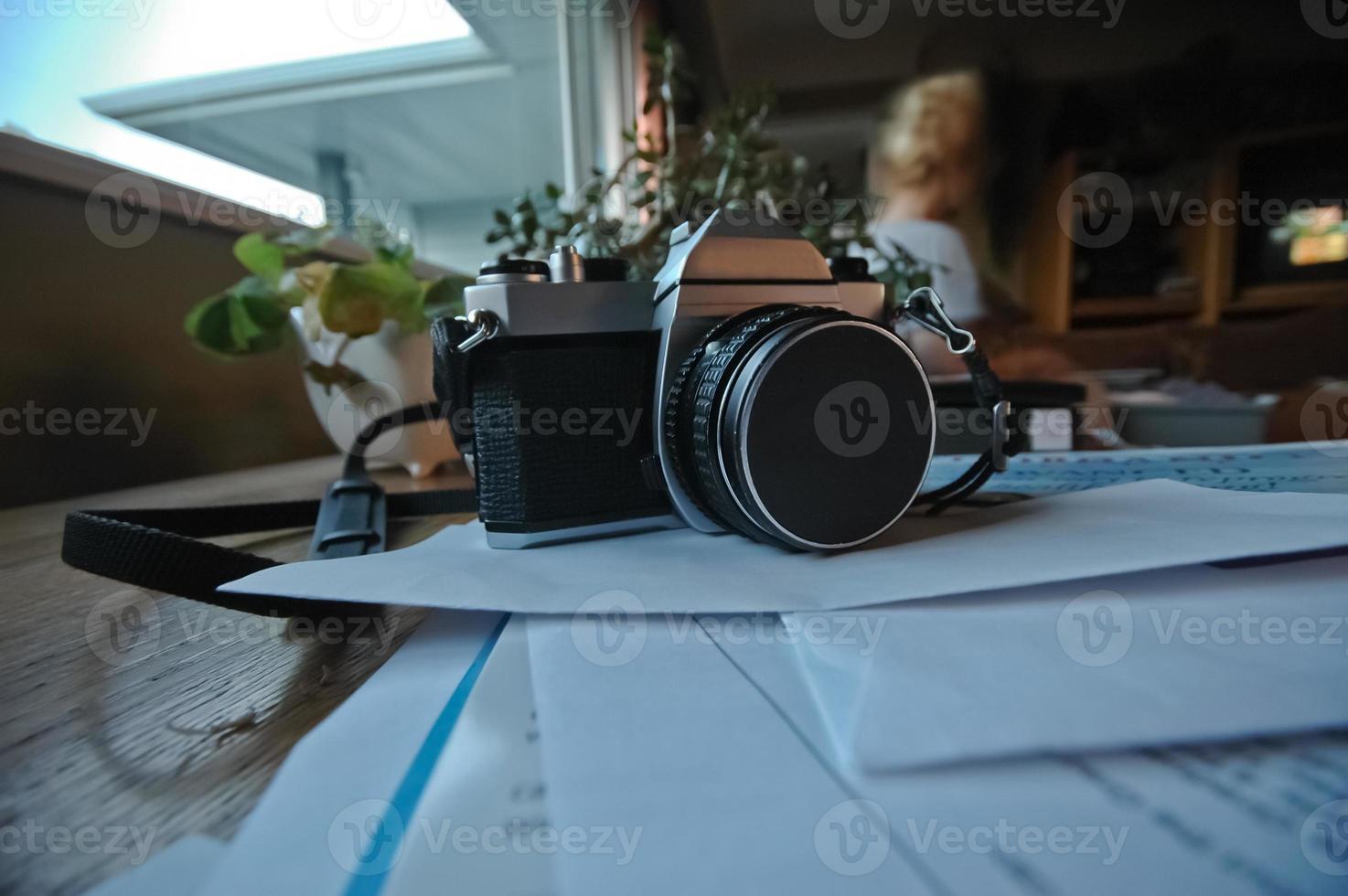 analogico in metallo classico vintage manuale a lente singola riflette la fotocamera su una pila di documenti in un soggiorno foto