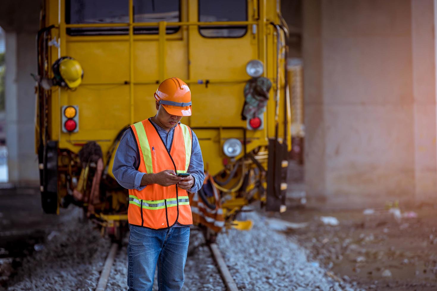 ingegnere ferroviario in fase di controllo del processo di costruzione test del treno e controllo dei lavori ferroviari sulla stazione ferroviaria con comunicazione radio. ingegnere che indossa l'uniforme di sicurezza e il casco di sicurezza sul lavoro. foto