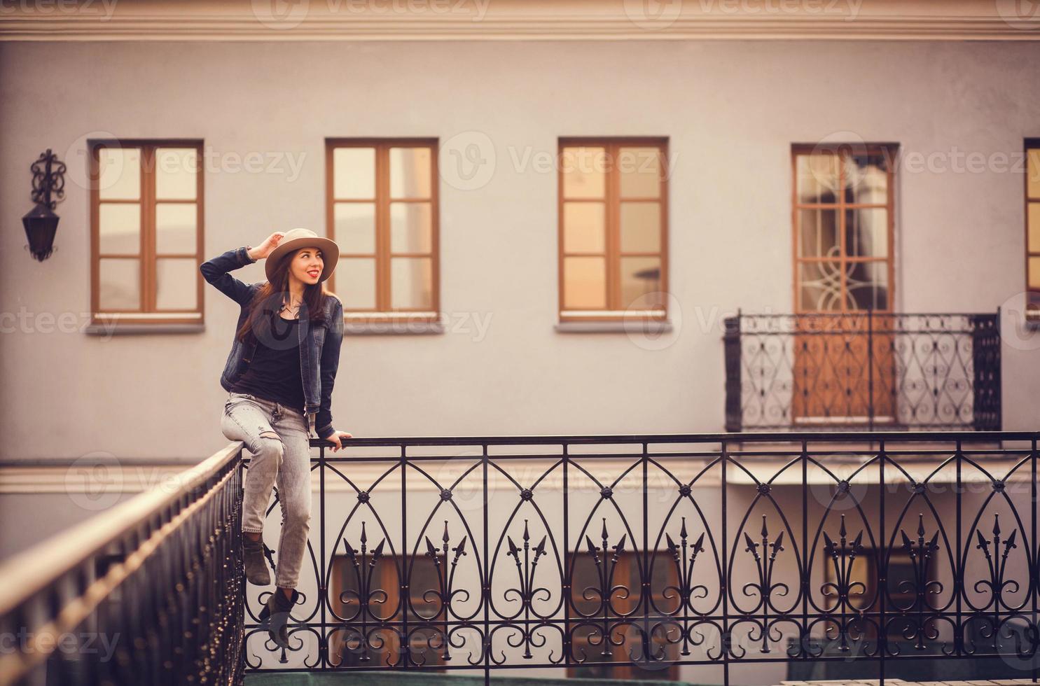 ragazza positiva seduta sulla ringhiera vicino all'edificio foto