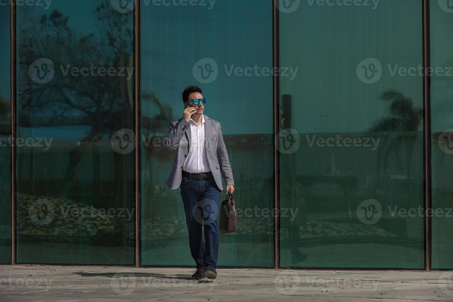 uomo d'affari con smartphone che cammina per strada foto