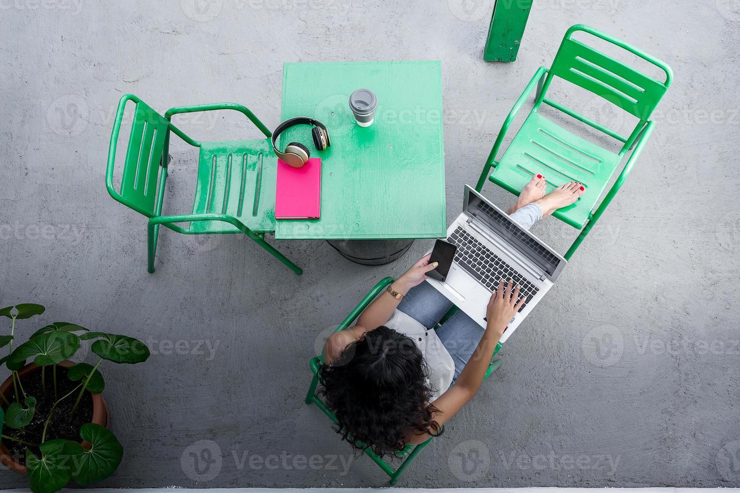 libero professionista irriconoscibile con smartphone e laptop in terrazza foto