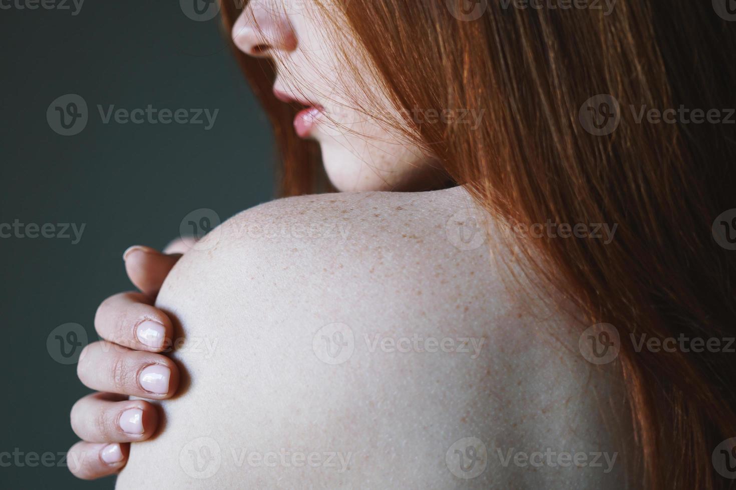 giovane donna con capelli rossi e lentiggini sulla spalla nuda foto
