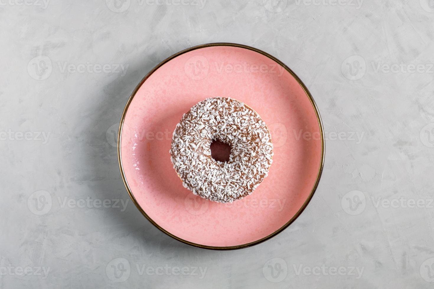 la ciambella con guarnizione di cocco si trova su un piatto di ceramica rosa foto