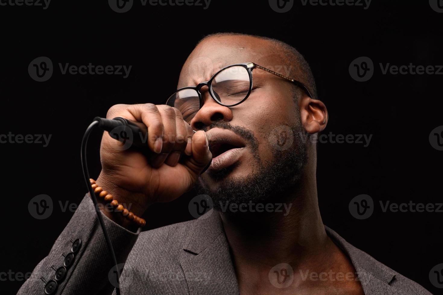un afroamericano nero sta cantando emotivamente in un microfono. ritratto in studio ravvicinato. foto