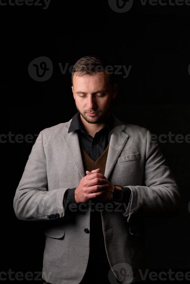 ritratto in studio di un giovane uomo caucasico in un blazer nero, guardando la telecamera, in piedi su sfondo semplice studio foto