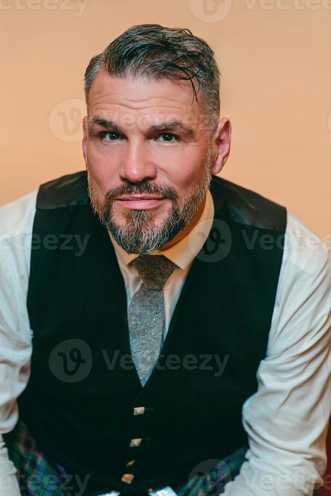 bel uomo maturo coraggioso ed elegante scozzese in kilt in una camera d'albergo elegante. stile, moda, stile di vita, cultura, viaggi, concetto etnico. foto