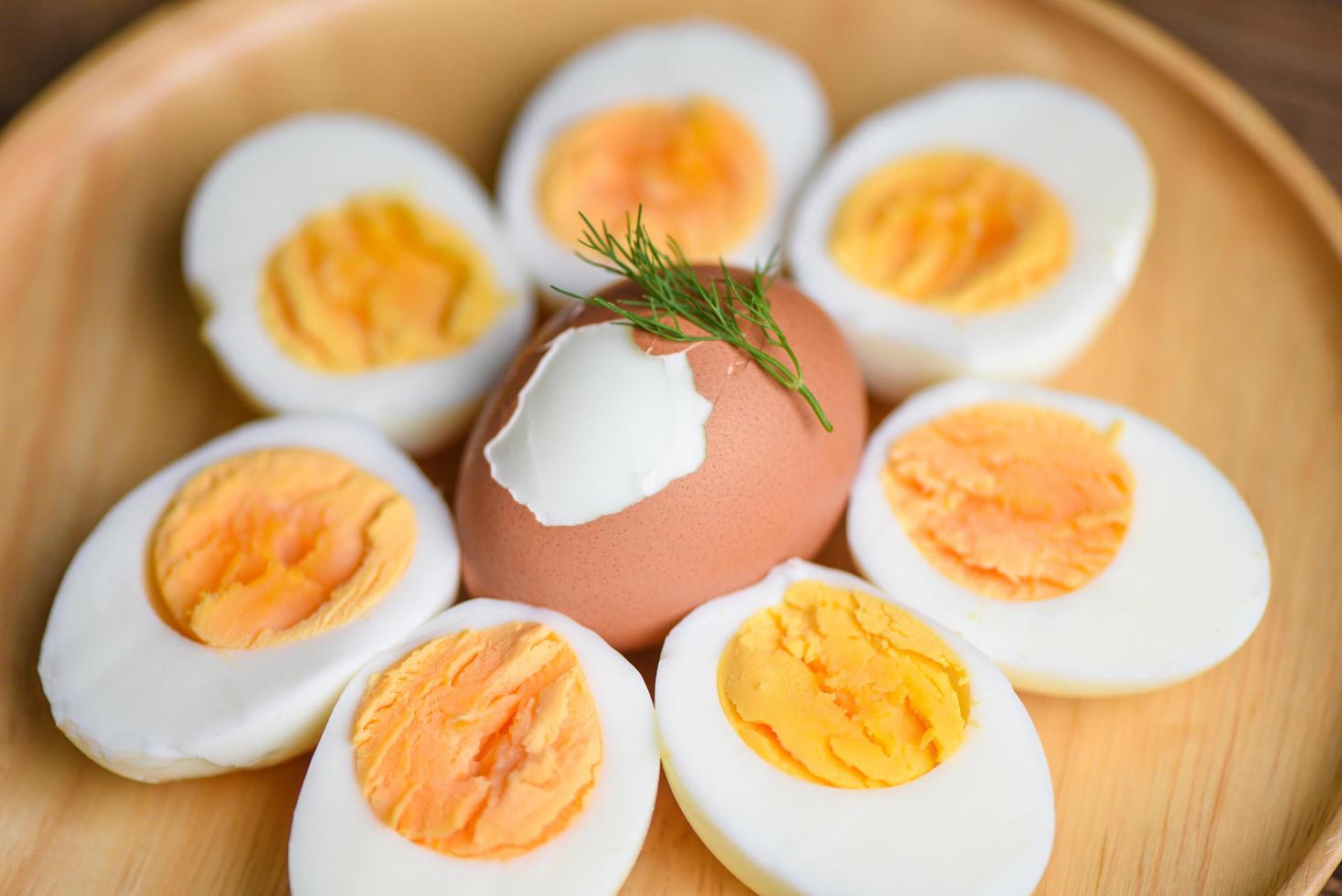 uova colazione, uova fresche menu cibo uova sode in un piatto di legno decorato con foglie sfondo verde aneto, tagliato a metà tuorli d'uovo per cucinare mangiare sano foto