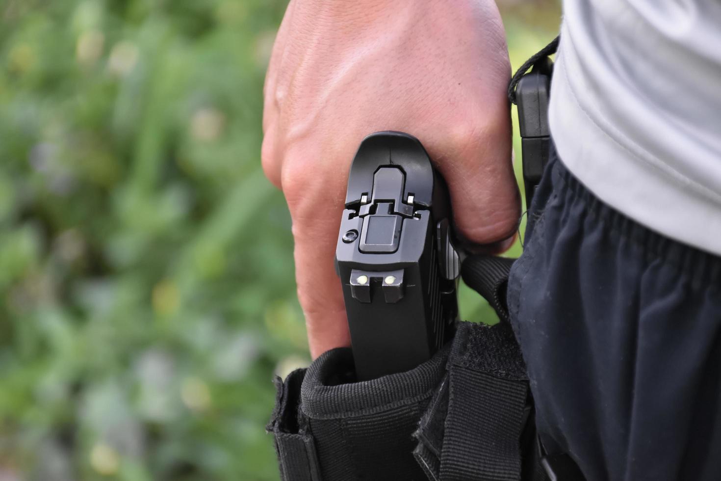 pistola automatica da 9 mm che tiene in mano la fondina, è pronta per essere tirata fuori e pronta a sparare al bersaglio davanti, concetto per la professione di sicurezza e lo sport di tiro in tutto il mondo. foto