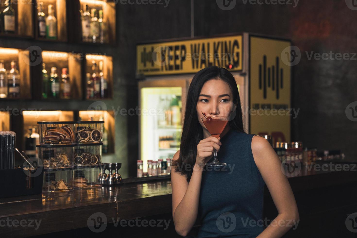 donna asiatica che beve un cocktail in un bar di notte. foto