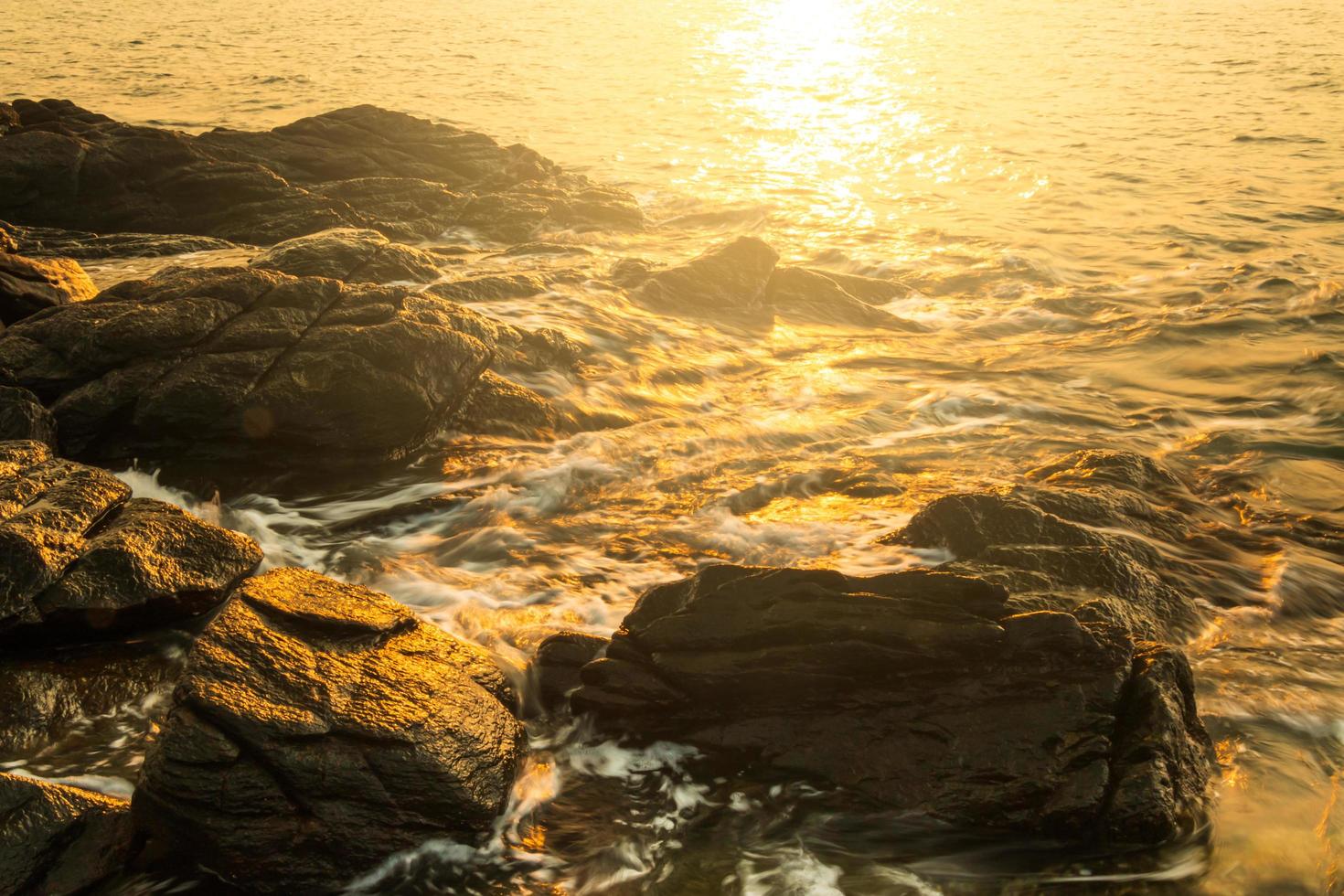 spiaggia rocciosa con acqua liscia e luce solare al mattino. foto