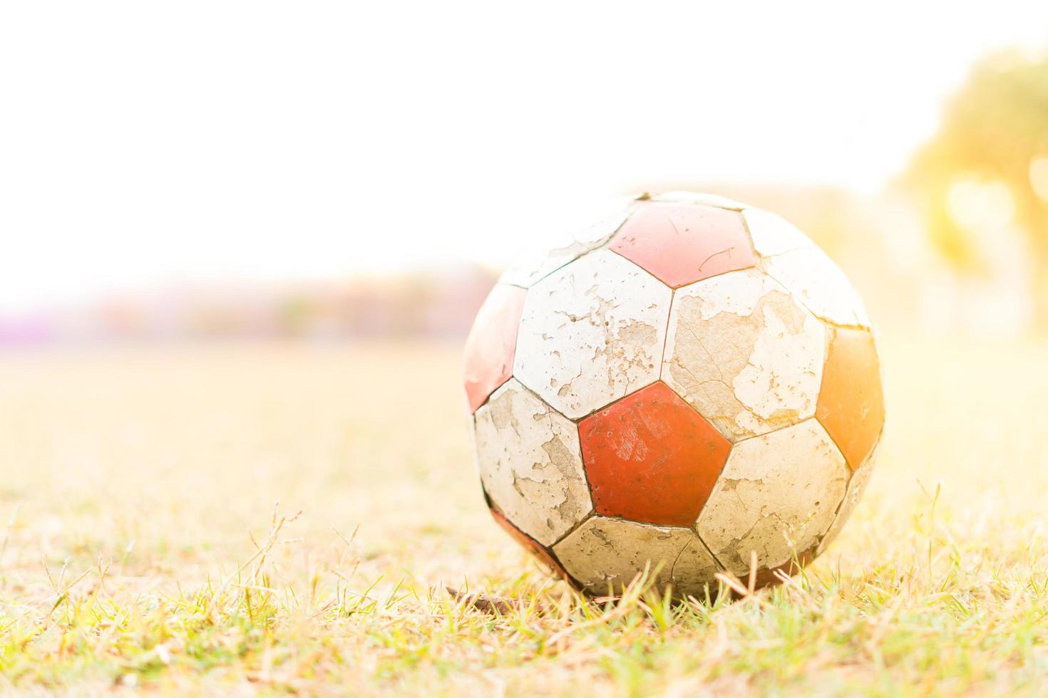 il vecchio calcio rosso e bianco sul campo in erba con la luce del sole. foto