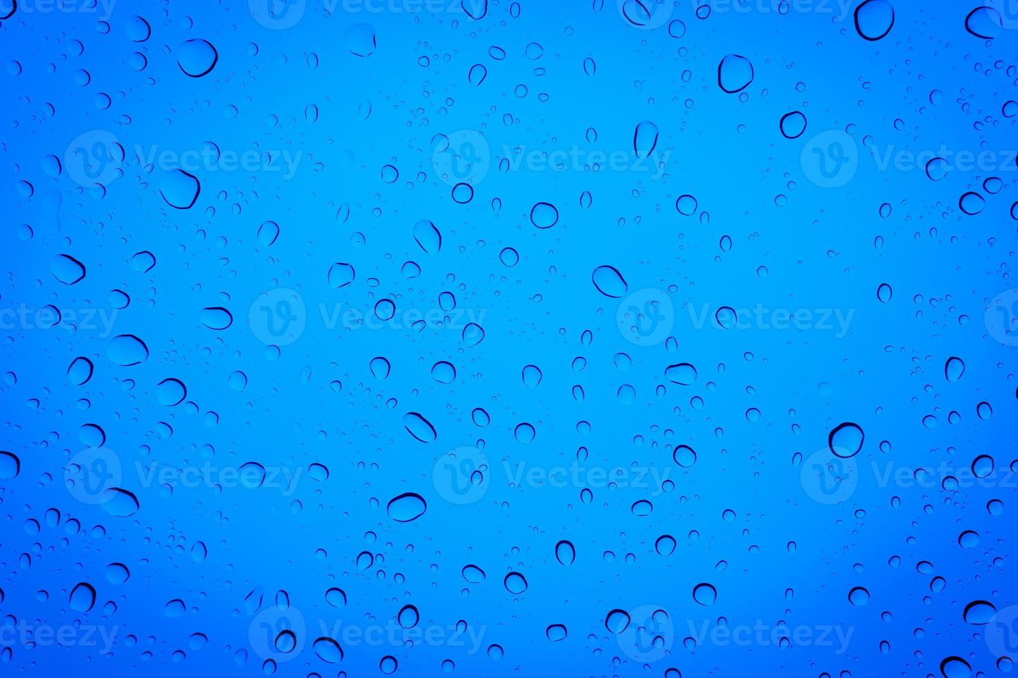 gocce d'acqua su un vetro blu, sfondo blu astratto. foto