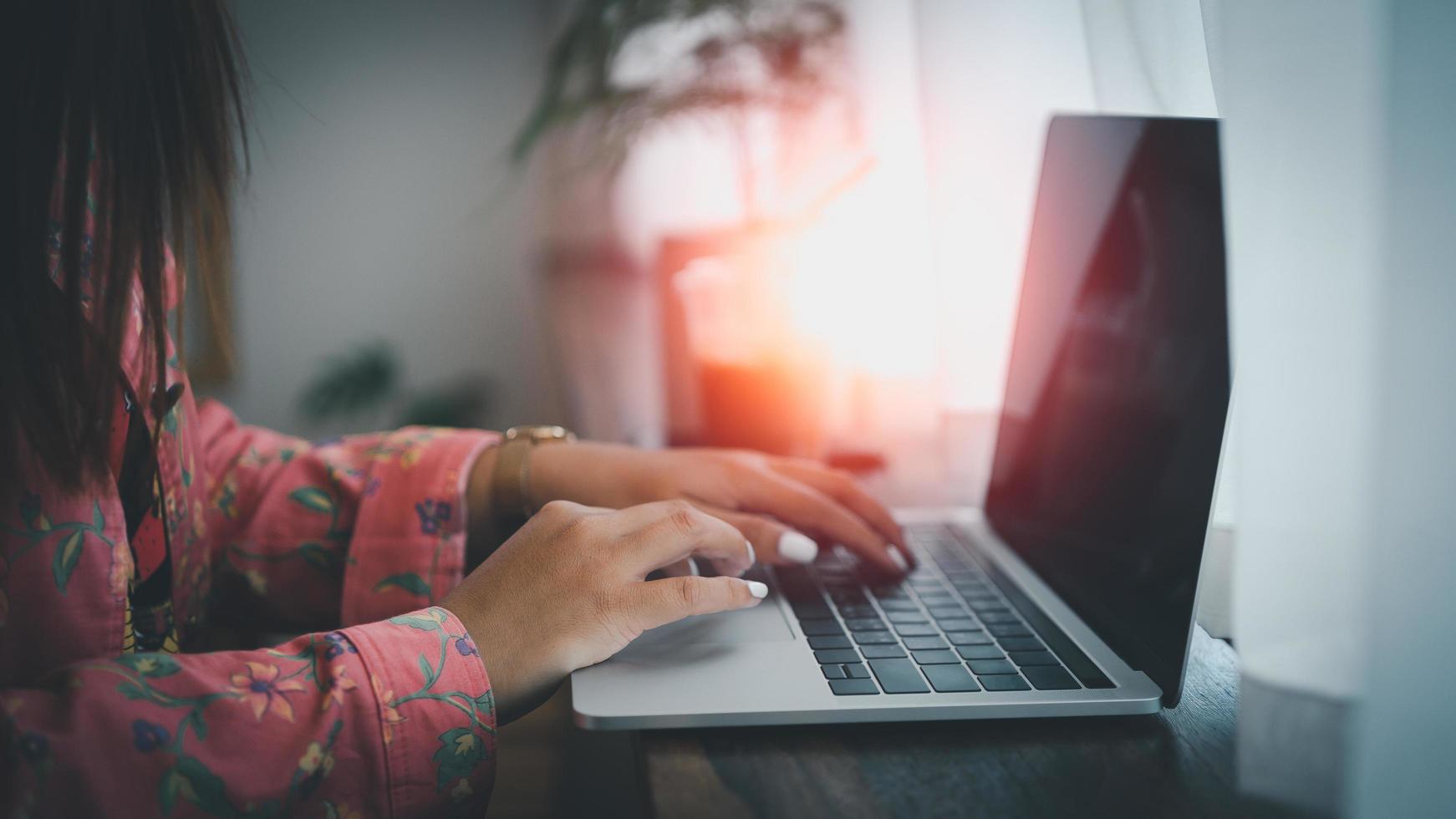 donna asiatica che lavora al computer portatile mentre è seduto in un ufficio creativo o in un bar. ragazza asiatica che lavora con il computer portatile sul tavolo di legno nella caffetteria. foto