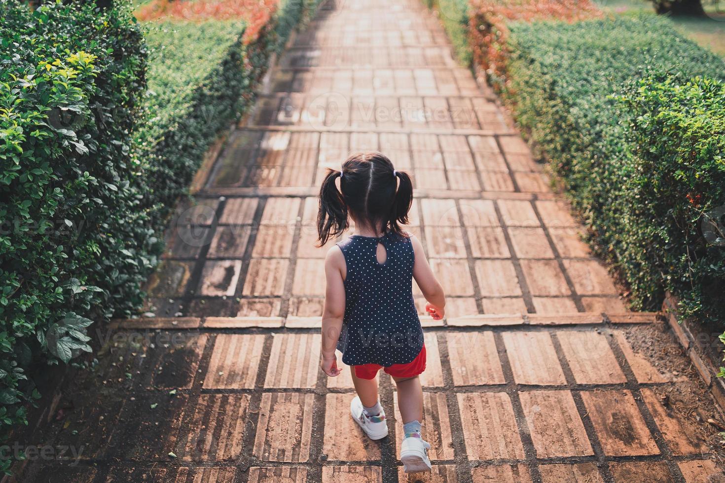 vista dal retro. ragazza che corre giù per le scale di mattoni nel parco la sera, c'è una luce del tramonto. ragazza che cresce concetto di successo. foto