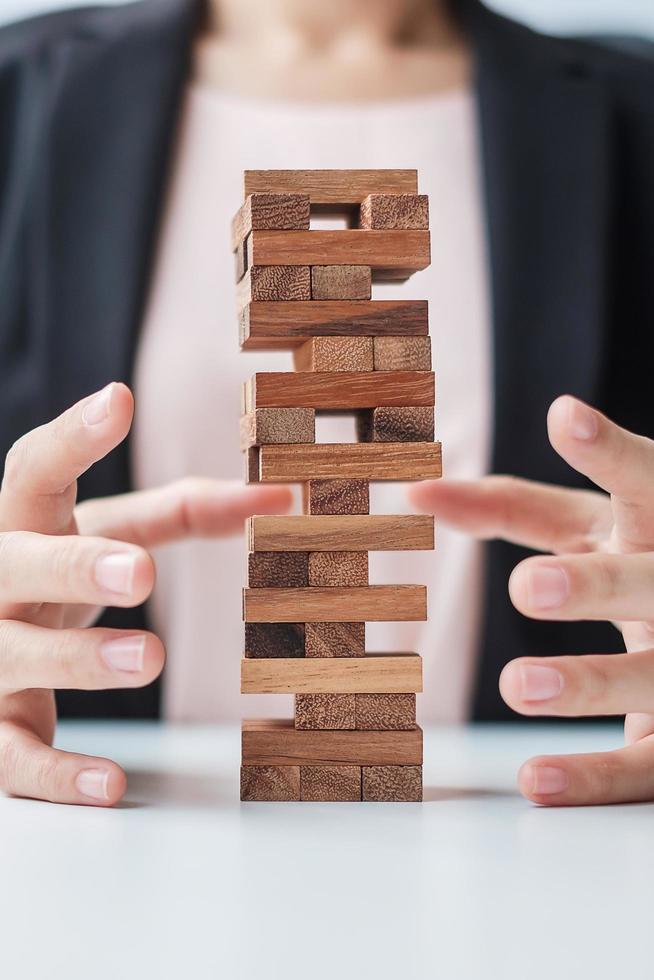 blocco di legno della copertura della mano della donna d'affari sulla torre. concetti di pianificazione aziendale, gestione del rischio, soluzione, assicurazione e strategia foto