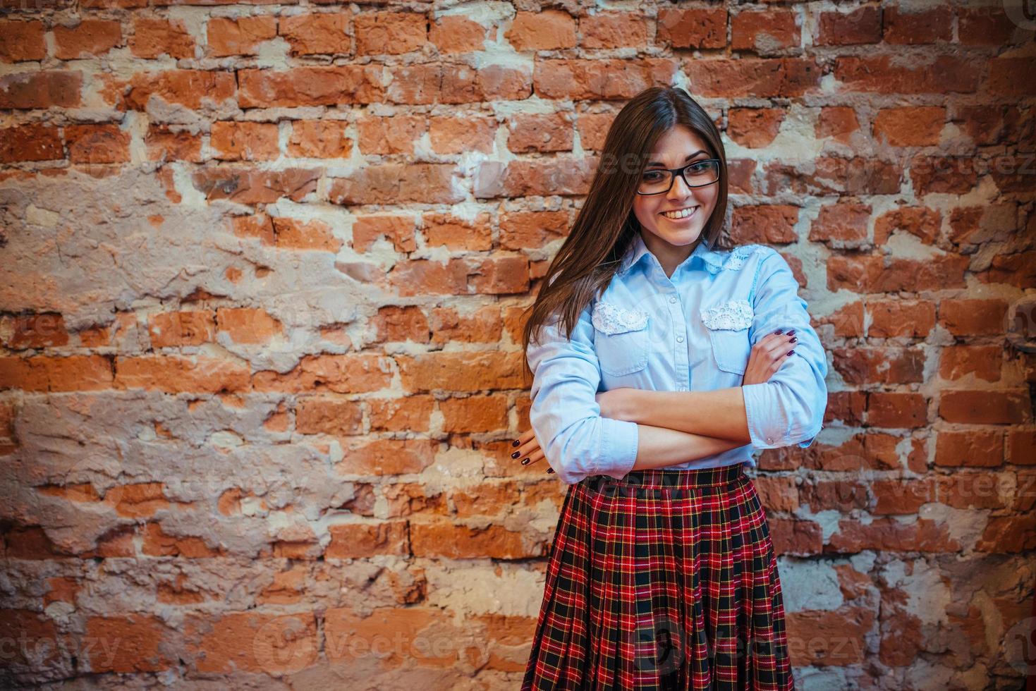 bella giovane donna si trova vicino al vecchio muro di mattoni. stile giovanile foto